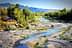 A river winding through a landscape with trees and rocky areas under a clear sky. - Olive Oil Times