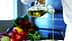 A person pouring olive oil from a glass bottle into a metal bowl in a kitchen setting. - Olive Oil Times