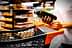 Individual holding a bottle of olive oil while standing next to a shopping cart in a store. - Olive Oil Times