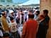 A group of people engaged in discussion at an outdoor event with a table displaying items. - Olive Oil Times