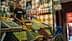 A market stall displaying a variety of olives and spices, with a vendor and a customer present. - Olive Oil Times