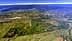 Aerial view showing extensive agricultural fields and mountainous terrain under a clear sky. - Olive Oil Times