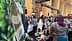 A booth displaying olive oil products at an exhibition with people interacting in the background. - Olive Oil Times