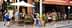 People dining outside at a restaurant with umbrellas and a brick facade on a street. - Olive Oil Times