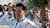 An athlete holding a medal and a laurel wreath while smiling at a crowd of photographers. - Olive Oil Times