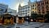 Wooden market stalls set up in an urban square with buildings in the background. - Olive Oil Times