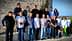 A group of individuals posing together outdoors in a casual setting, some holding bottles. - Olive Oil Times
