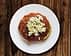 A plate of dakos salad featuring a base of barley rusk topped with tomato sauce and crumbled feta cheese. - Olive Oil Times
