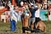Two men wrestling on the ground while a referee and spectators cheer in the background. - Olive Oil Times