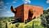 A large, red architectural building with a prominent spherical and cylindrical design element. - Olive Oil Times